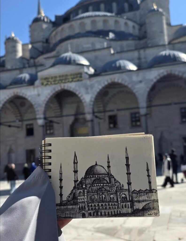 Detailed pen sketch of a domed mosque held in front of its architecture