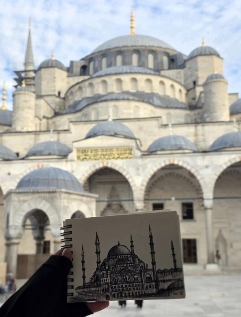 Hand-drawn mosque in a sketchbook held in front of the building