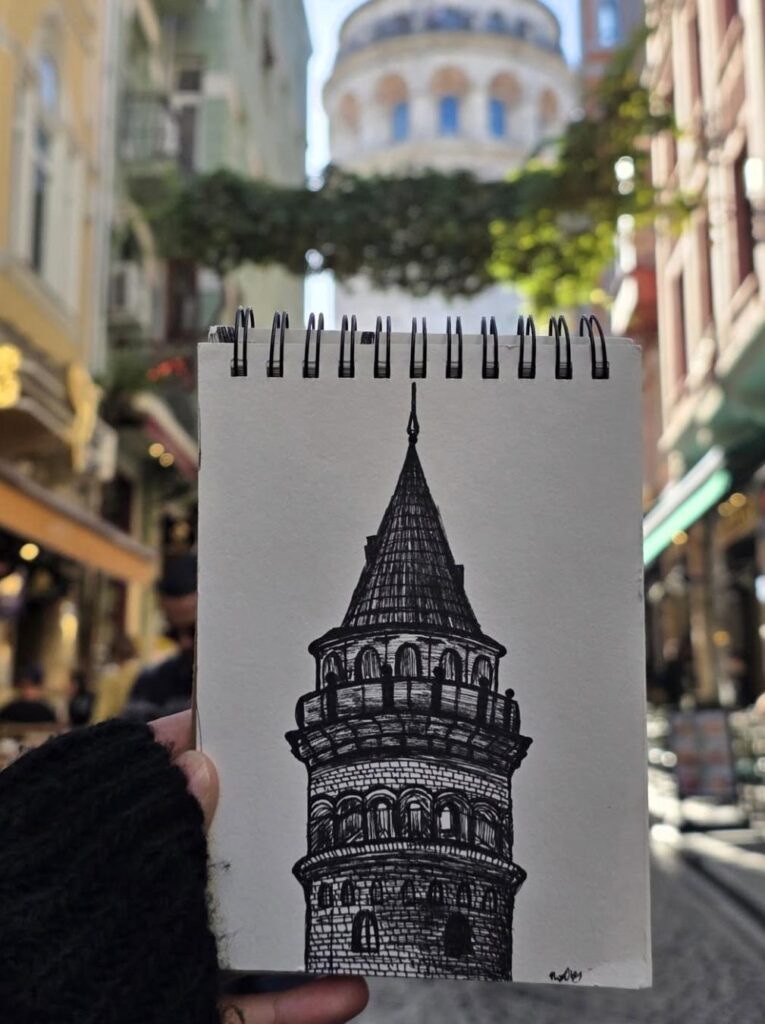 Hand-drawn tower sketch held in front of the tower on a city street